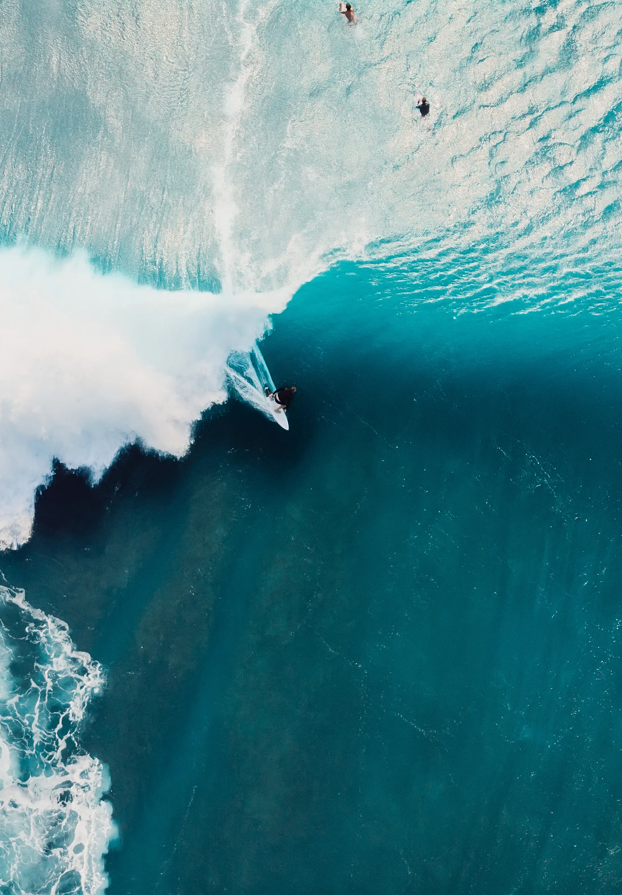 Aerial view of a surfer riding a turquoise wave